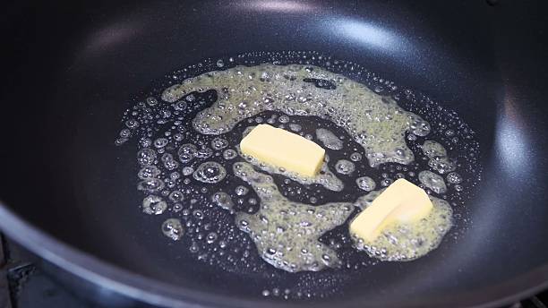 istock Two butter pieces melt in pan surrounded by bubbling liquid 2245370394