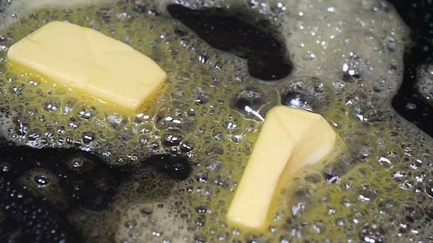 istock Two butter pieces melt in pan surrounded by bubbling liquid 2245370454