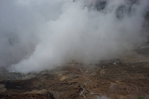 Ethereal landscape with geothermal activity creates a moody and dramatic scene, thick fog and steam veiling a desolate, brown terrain of otherworldly beauty and mystery.