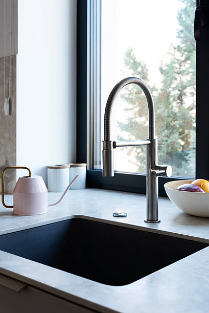 istock Kitchen sink with water tap by the window and kitchen counterpart. Home interior with modern design. Vertical 2245373840