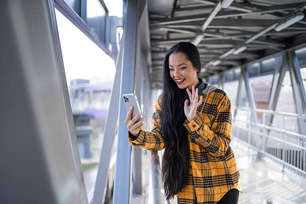 Young woman confidently chatting on her phone while walking along a modern urban bridge.