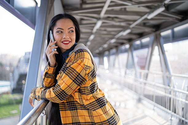 istock Young woman engaging in a phone call with a joyful expression on a bridge in an urban setting. 2245374854
