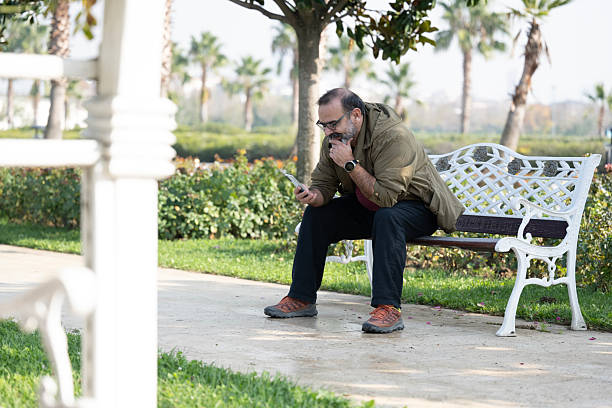 A man having fun outside in the park and using smart phone