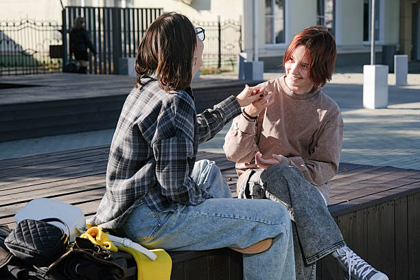 teen girl and mother sitting on a park bench talking and laughing