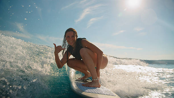 istock Caucasian Woman Surfing on Ocean Wave Under Bright Sky 2245377241