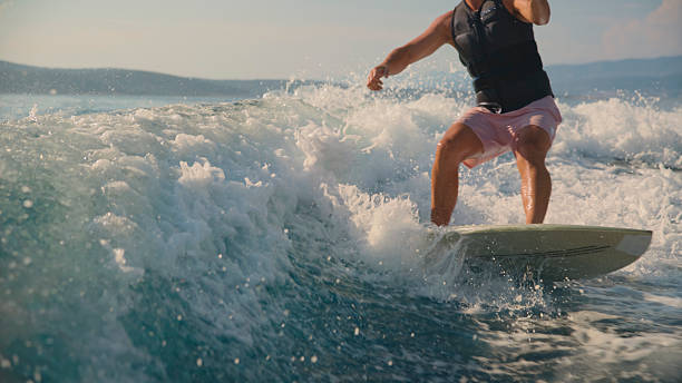 istock Young Man Wakeboarding on Sea Wave Behind Boat 2245377967