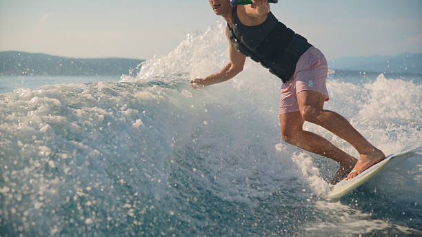 istock Young Man Wakeboarding on Sea Wave Behind Boat 2245377968