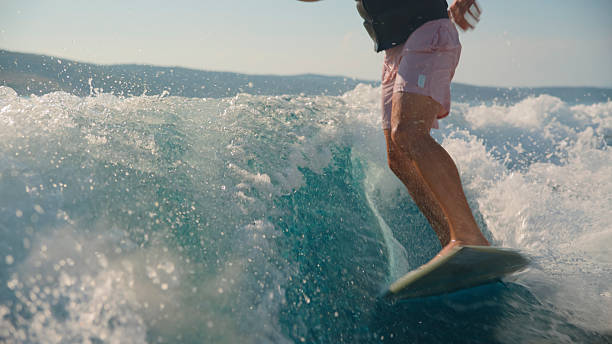 istock Low Angle View of Male Surfer Enthusiastically Riding Ocean Wave 2245377998