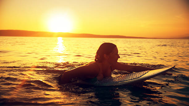 istock Caucasian Female Paddling Surfboard at Sunset 2245378060