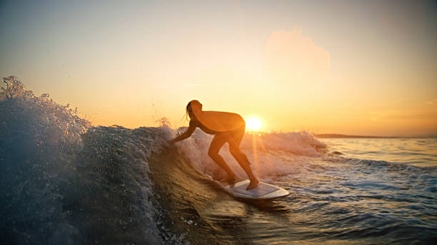 istock Joyful Young Caucasian Woman Surfing Ocean Wave During Sunset 2245378346