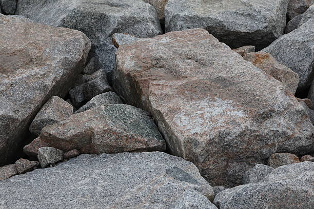 Close-up view of rugged granite breakwaters arranged along a shoreline to prevent erosion.