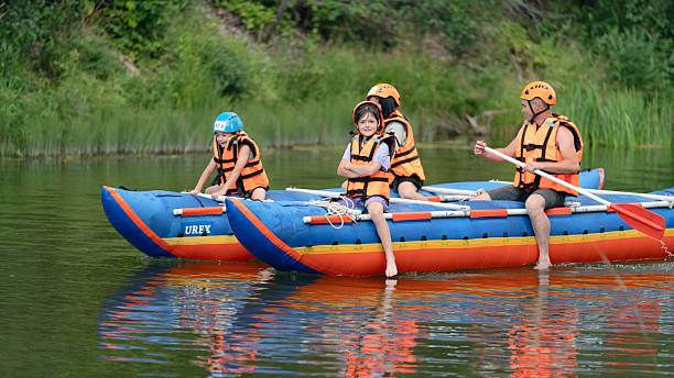 Russia, Republic of Bashkortostan, Kugarchinsky District, Bikbulatovo Village – August 5, 2023. Children and parents are sailing on an inflatable catamaran down the river. A real childhood experience.