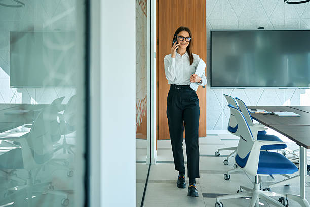 istock Businesswoman walking in modern office having phone call 2245383387