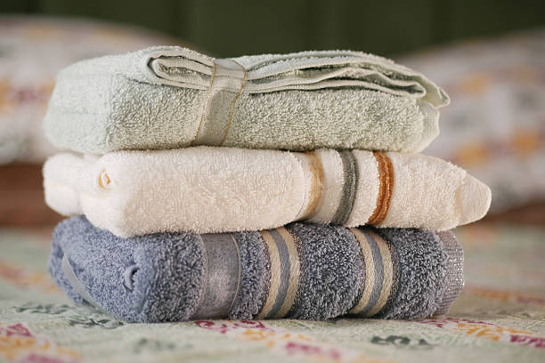Soft towels are stacked neatly on a patterned bed spread in a cozy room.