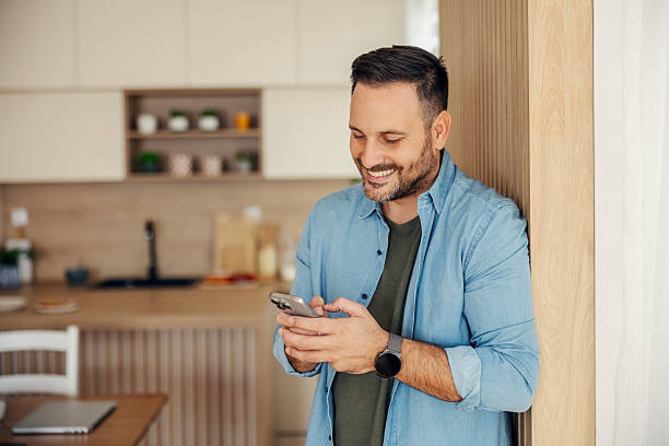 istock Smiling man texting on smartphone at home kitchen 2245390953