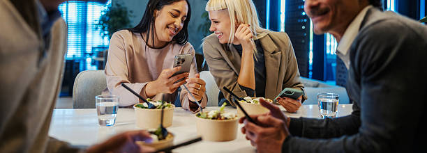 istock Colleagues smiling and sharing smartphone during office lunch break 2245391554