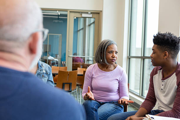 istock Diverse group of adults engage in a thoughtful discussion during a support session. 2245393264