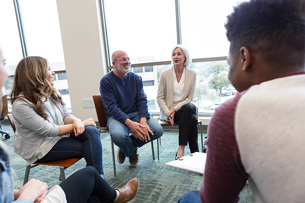 istock Diverse group of adults engaged in a supportive discussion session with a therapist present. 2245393316