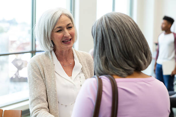 istock Two women engage in friendly conversation indoors, smiling and making eye contact. 2245393324
