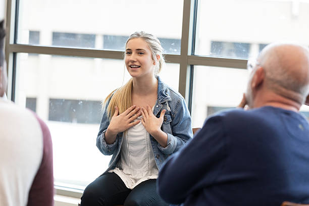 istock Young woman shares her feelings with a group during a therapy session. 2245393340