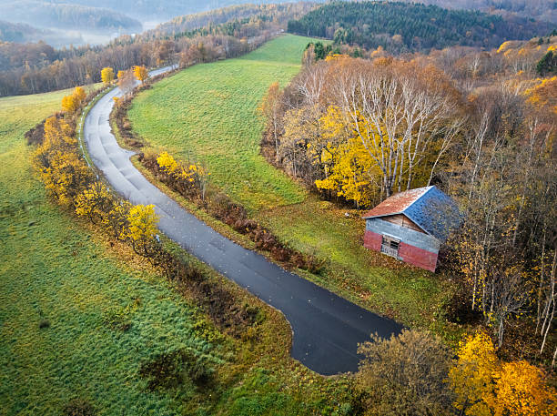 Aerial view of an autumn forest landscape in the hills of north Hokkaido with a run-down abandoned shack amongst the colorful trees.
