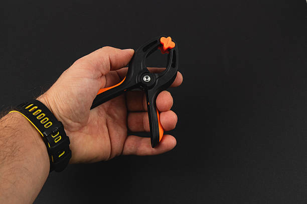 istock Hand holding a black and orange plastic clamp tool in bright light 2245397856