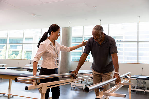 istock Physical therapist assists senior man using parallel bars during rehabilitation therapy session indoors. 2245398362