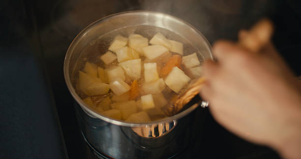 A close-up view of diced swede and carrot cooking in a boiling pot at home