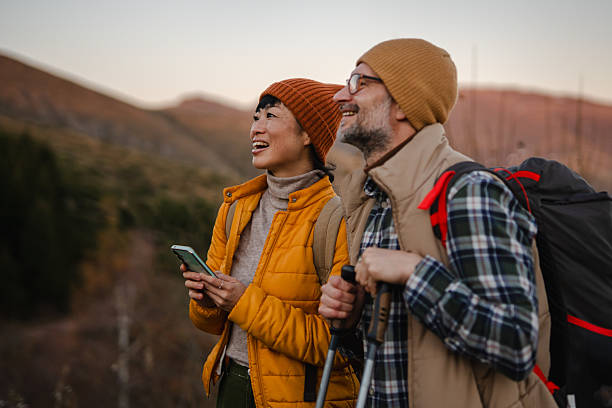 Couple enjoying mountain hiking adventure using smart phone for navigation