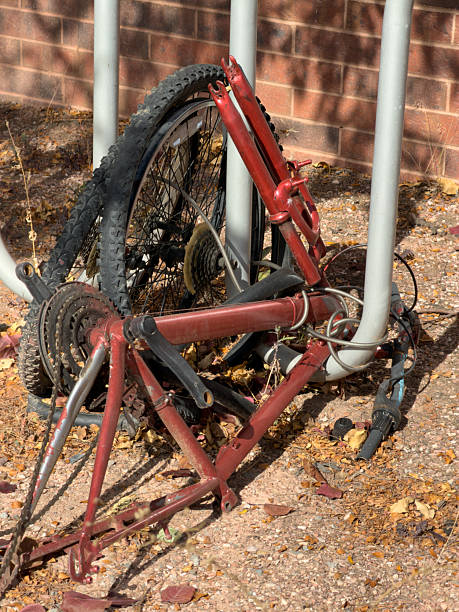 Broken red bicycle frame and wheel remain attached to a metal bike rack