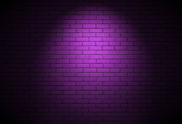 istock Brick wall lit by street light at night time - dark alley background texture 2245402810