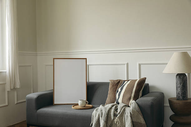 istock Aesthetic A2 wooden picture frame mockup on grey sofa couch near window. Coffee cup, wool plaid, marble lamp on side table.e table. Modern Scandinavian home interior, beige wall background 2245404026