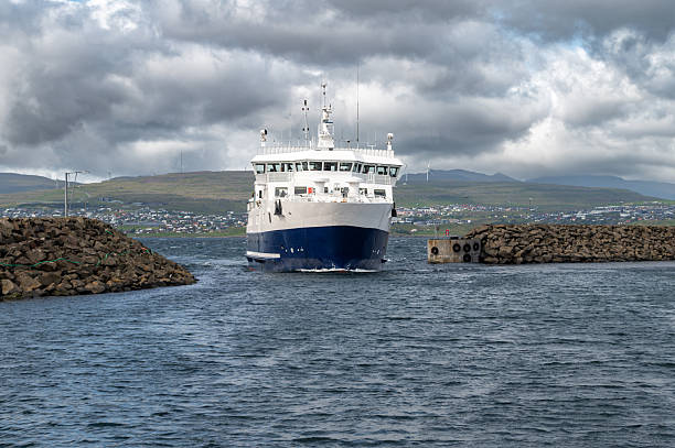 Passenger ferry arriving at Nolsoy, Faroe Islands, with scenic coastal landscape, colorful houses, and calm North Atlantic waters.