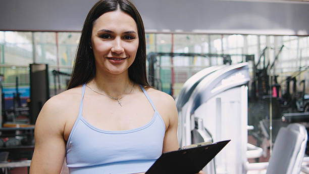 istock Fitness trainer guiding clients in a gym setting while holding a clipboard and smiling confidently 2245405627