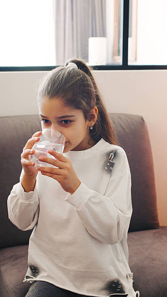 istock Young girl enjoys a water while sitting on a cozy couch in a bri 2245407167