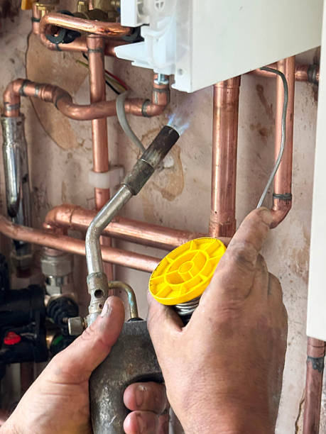 istock Full frame image of unrecognisable plumber soldering copper piping, dirty hands holding blow torch with burning gas flame and reel of soldering metal alloy, focus on foreground 2245409070