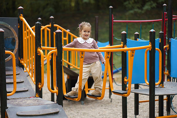 Young girl smiling while engaging in playground equipment play.