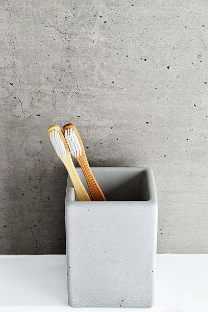 istock Eco-friendly wood toothbrushes with soft white bristles in modern grey concrete holder. Minimal bathroom design, sustainable hygiene concept, Neutral tones, zerowaste lifestyle, eco-conscious living 2245420347