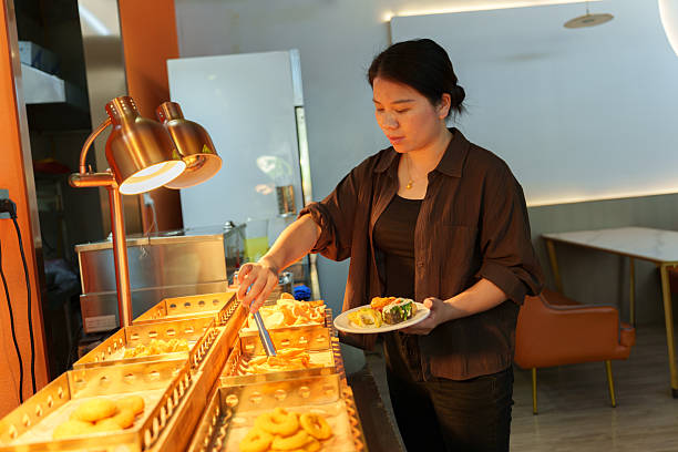 istock An Asian female customer getting food from the buffet. 2245421762