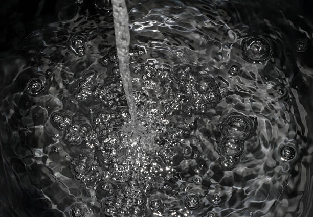 Stream of Water Splashing and Creating Ripples and Bubbles in a Container