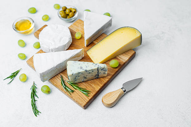 istock Cheese platter featuring various cheeses, olives, and grapes on wooden board 2245423626