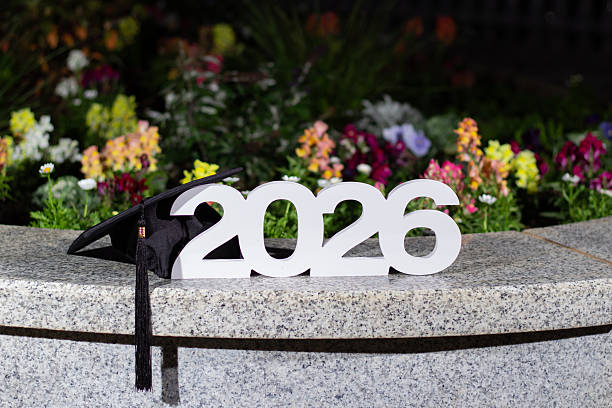istock Celebrating Graduation With 2026 Display and a Cap on a Stone Bench Decorated With Flowers at Night 2245425103