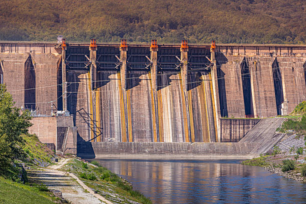 istock Concrete dam wall with multiple spillways holding back river water, using sustainable energy for electricity generation 2245428455