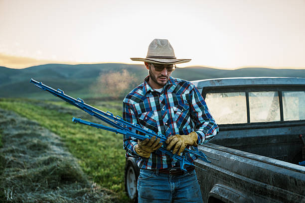istock Rancher Unloading Fence Posts from Truck at Sunrise 2245429642