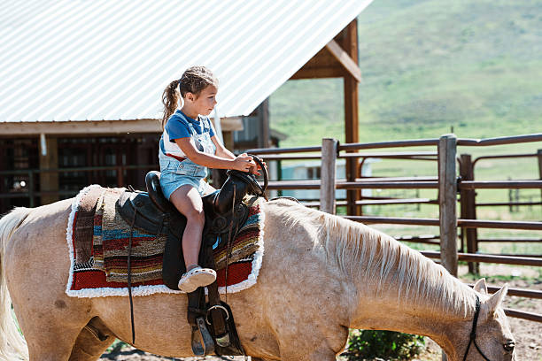 A young girl rides a horse while her family visits friends at a Wyoming ranch during summer vacation.