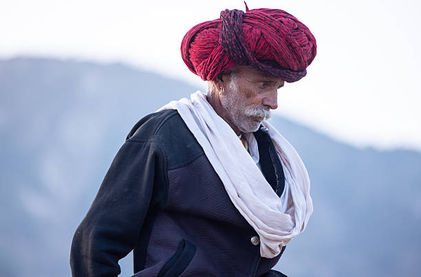 Pushkar, Rajasthan, India - November 2024: Portrait of a rajasthani male in traditional white clothes with colourful turban at desert fair ground during the pushkar camel fair to trade camels.