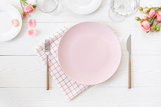 istock Festive table setting with empty plate and glasses, cutlery and napkin - roses flowers decorated, flat lay. Top view 2245436479
