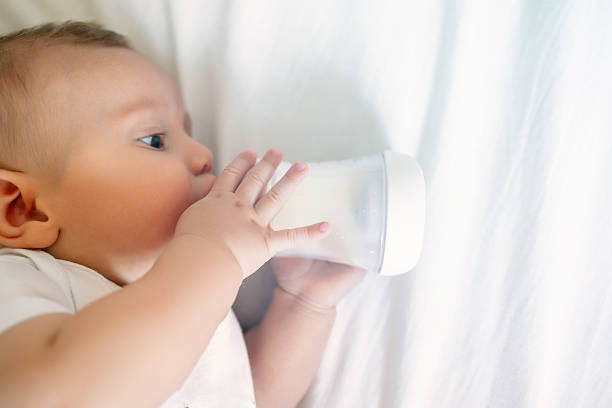 istock Baby boy drinking milk from bottle lying on bed 2245441303