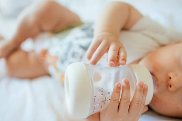 istock bottle feeding newborn son daughter lying on bed drink milk 2245441322