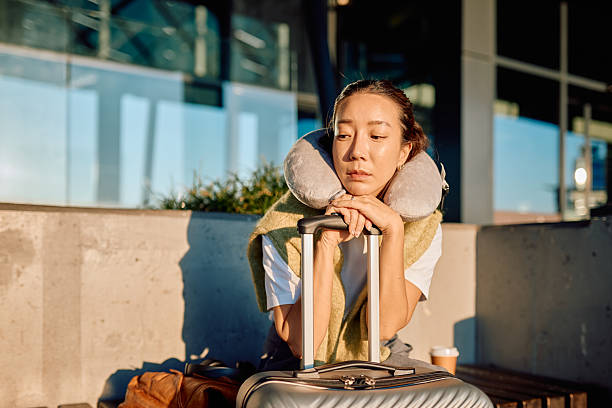 Woman feeling tired and sad, patiently waiting at the airport terminal with her luggage due to a flight delay or cancellation